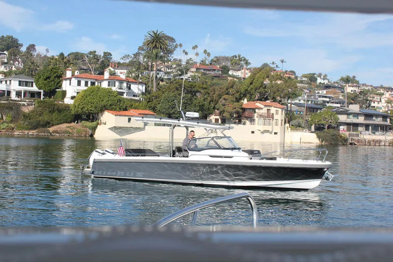 San #155 In Stock Yacht Photos Pics 2024 Nimbus T9 boat cruising near waterfront homes, clear sky, calm water.