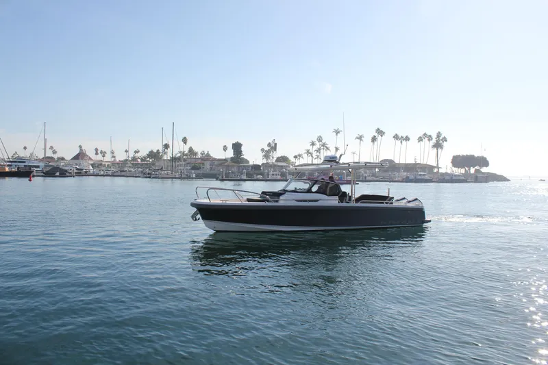 San #155 In Stock Yacht Photos Pics Nimbus T9 2024 boat cruising in a sunny marina with palm trees in the background.