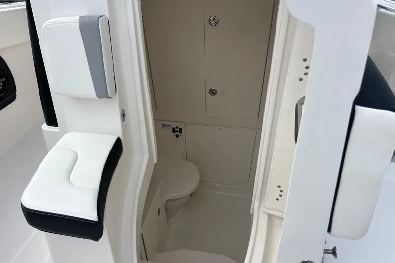  Yacht Photos Pics 2025 Robalo R300 Center Console interior with compact marine toilet and cushioned seating.