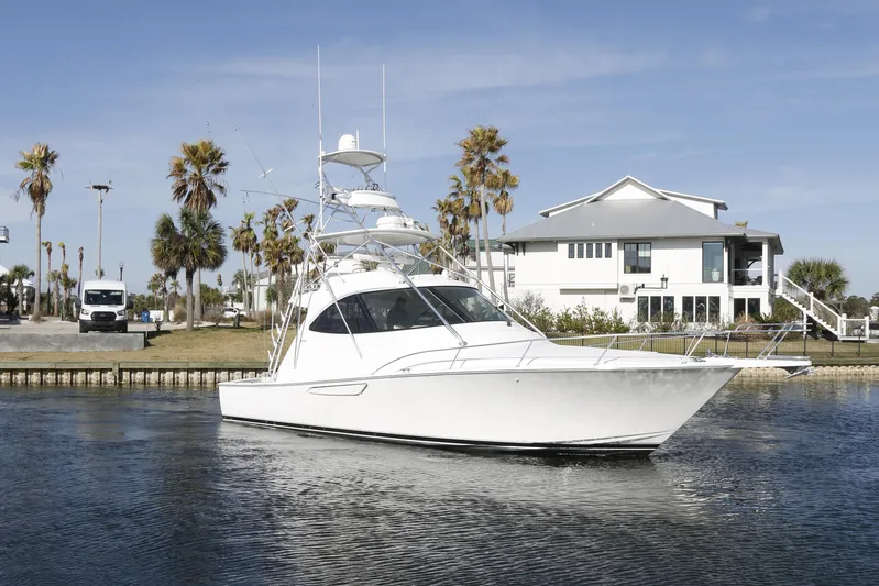 Brown Eyed Girl Yacht Photos Pics 2014 Viking 42 Sport Tower yacht docked near a waterfront house with palm trees.