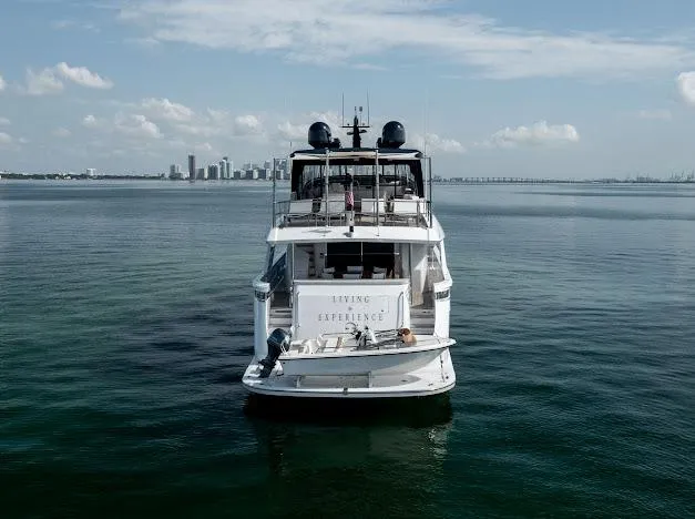 Living The Experience Yacht Photos Pics Hatteras 100 Raised Pilothouse 2015 yacht on calm waters with city skyline in background.