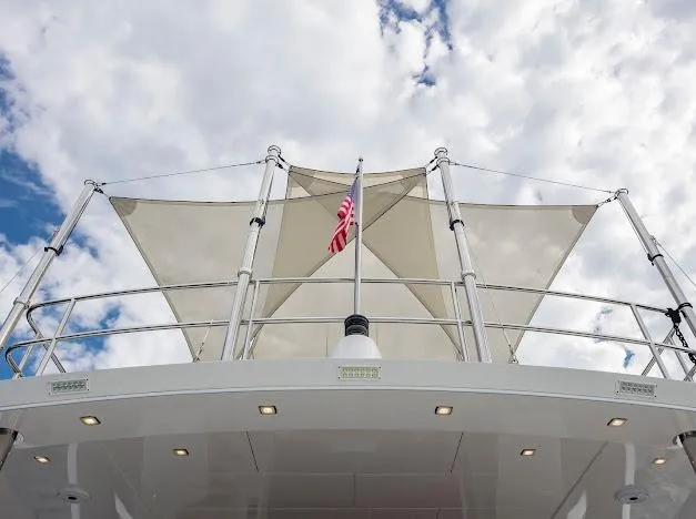Living The Experience Yacht Photos Pics 2015 Hatteras 100 Raised Pilothouse yacht with sunshade and American flag.