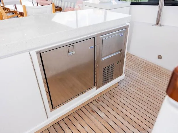 Living The Experience Yacht Photos Pics Outdoor kitchen area on a 2015 Hatteras 100 Raised Pilothouse yacht with stainless steel appliances.