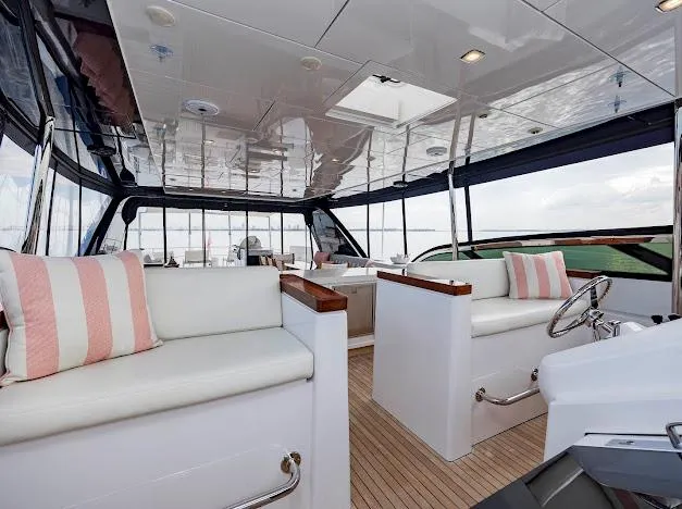 Living The Experience Yacht Photos Pics Interior of 2015 Hatteras 100 Raised Pilothouse yacht with white seating and striped cushions.