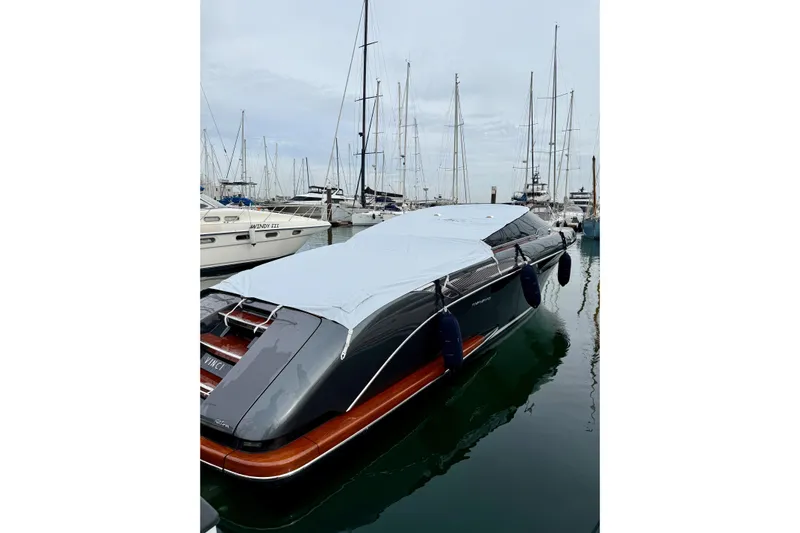  Yacht Photos Pics 2025 Riva Rivamare yacht docked, covered with a protective tarp, surrounded by sailboats.