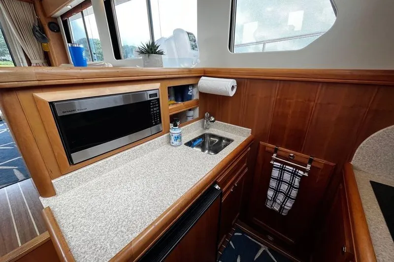  Yacht Photos Pics 2006 Mainship 34 Trawler galley with microwave, sink, and wooden cabinetry.