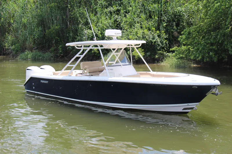  Yacht Photos Pics 2016 Pursuit S 280 Sport boat on calm water, surrounded by lush greenery.