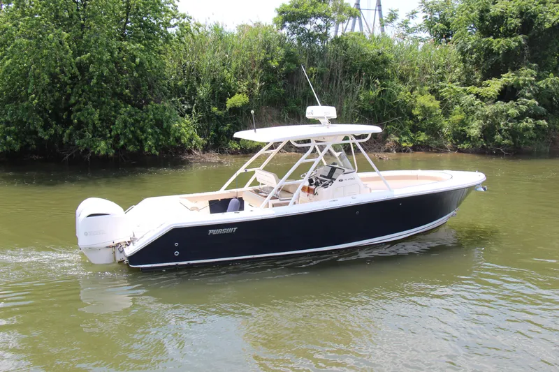  Yacht Photos Pics 2016 Pursuit S 280 Sport boat cruising on a calm river, surrounded by lush greenery.