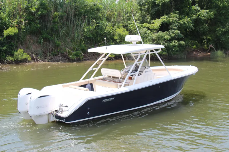  Yacht Photos Pics 2016 Pursuit S 280 Sport boat on calm water, surrounded by lush greenery.