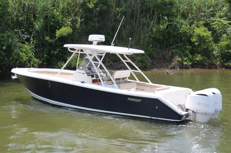  Yacht Photos Pics 2016 Pursuit S 280 Sport boat on calm water near lush greenery.