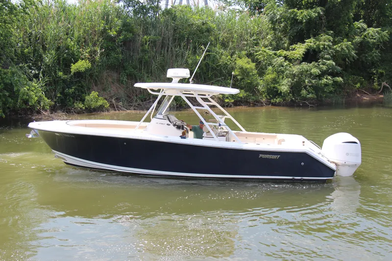  Yacht Photos Pics 2016 Pursuit S 280 Sport boat cruising on a calm river near lush greenery.