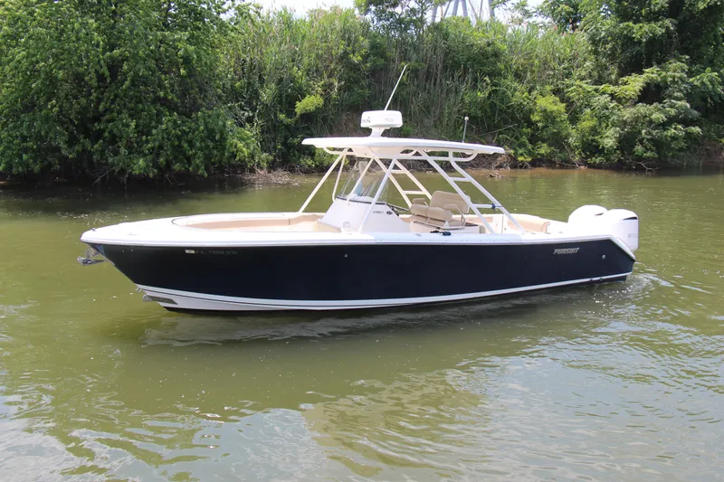  Yacht Photos Pics 2016 Pursuit S 280 Sport boat on calm water, surrounded by lush greenery.