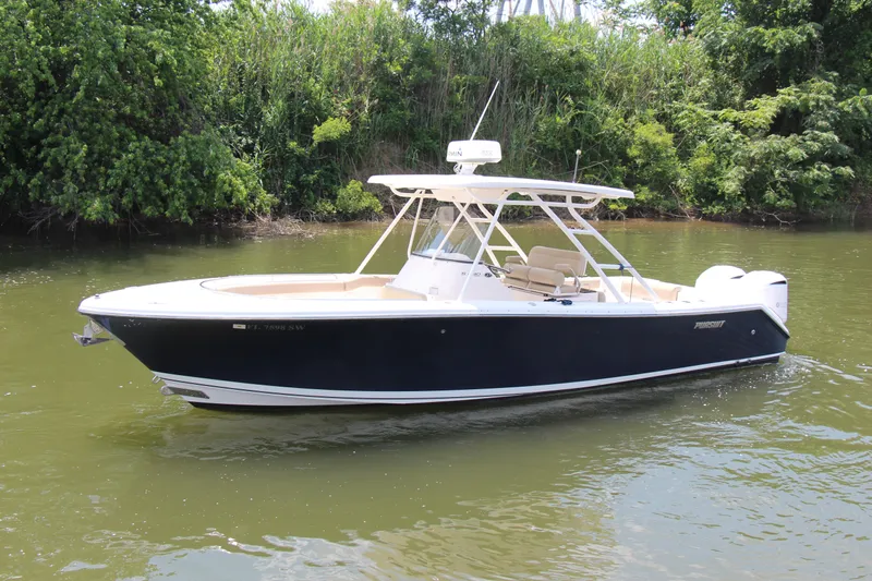  Yacht Photos Pics 2016 Pursuit S 280 Sport boat on calm water, surrounded by lush greenery.