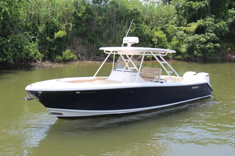  Yacht Photos Pics 2016 Pursuit S 280 Sport boat on calm water, surrounded by lush greenery.