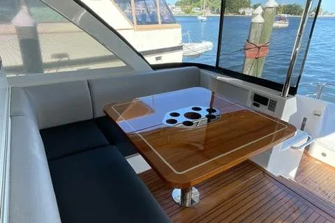 Yacht Photos Pics Luxurious 2025 Riviera 585 SUV yacht interior with elegant wooden table and waterfront view.