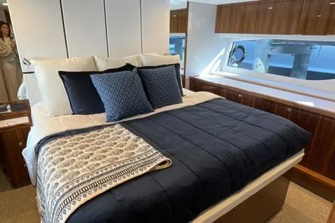  Yacht Photos Pics Luxurious bedroom interior of 2025 Riviera 585 SUV yacht with elegant bedding and wood accents.