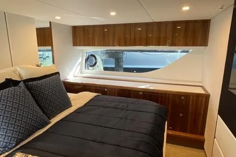  Yacht Photos Pics Luxurious bedroom interior of 2025 Riviera 585 SUV yacht with elegant wood finishes.