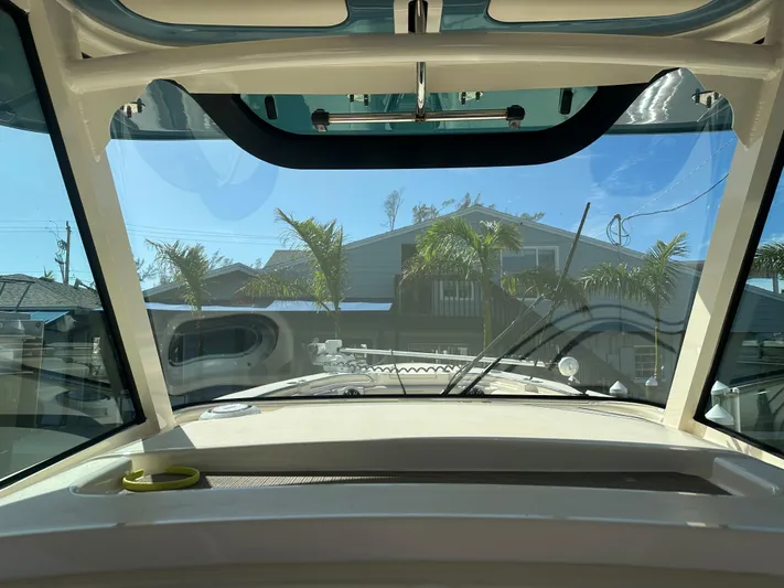  Yacht Photos Pics Interior view of 2021 Grady-White 336 Canyon boat with clear windshield and palm trees outside.
