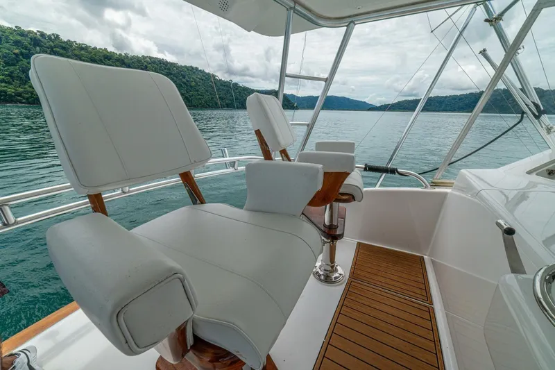 Mariah Jean Yacht Photos Pics Luxury seating on a 2004 Viking 61c yacht, overlooking serene waters and lush hills.
