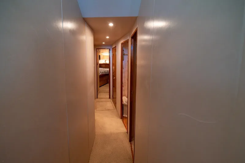Mariah Jean Yacht Photos Pics Narrow hallway inside 2004 Viking 61 Convertible yacht, featuring carpeted floor and wooden doors.