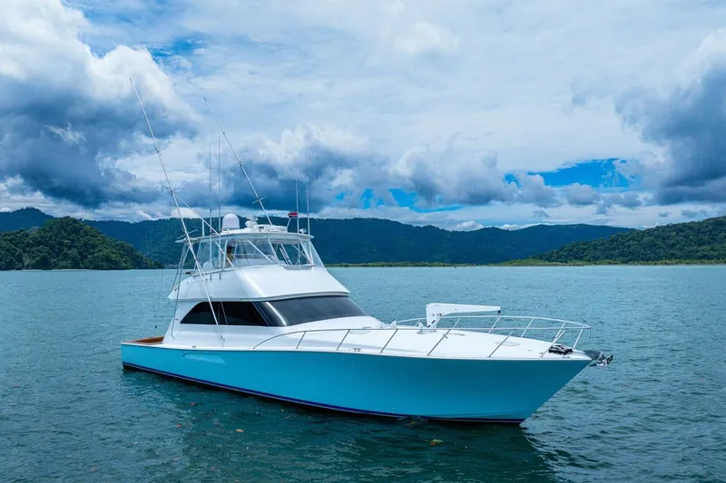 Mariah Jean Yacht Photos Pics 2004 Viking 61c yacht on serene water with lush green hills and cloudy sky.