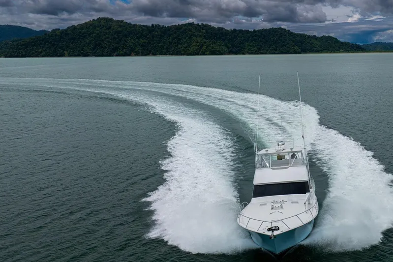 Mariah Jean Yacht Photos Pics A 2004 Viking 61c yacht cruising on open water with lush hills in the background.