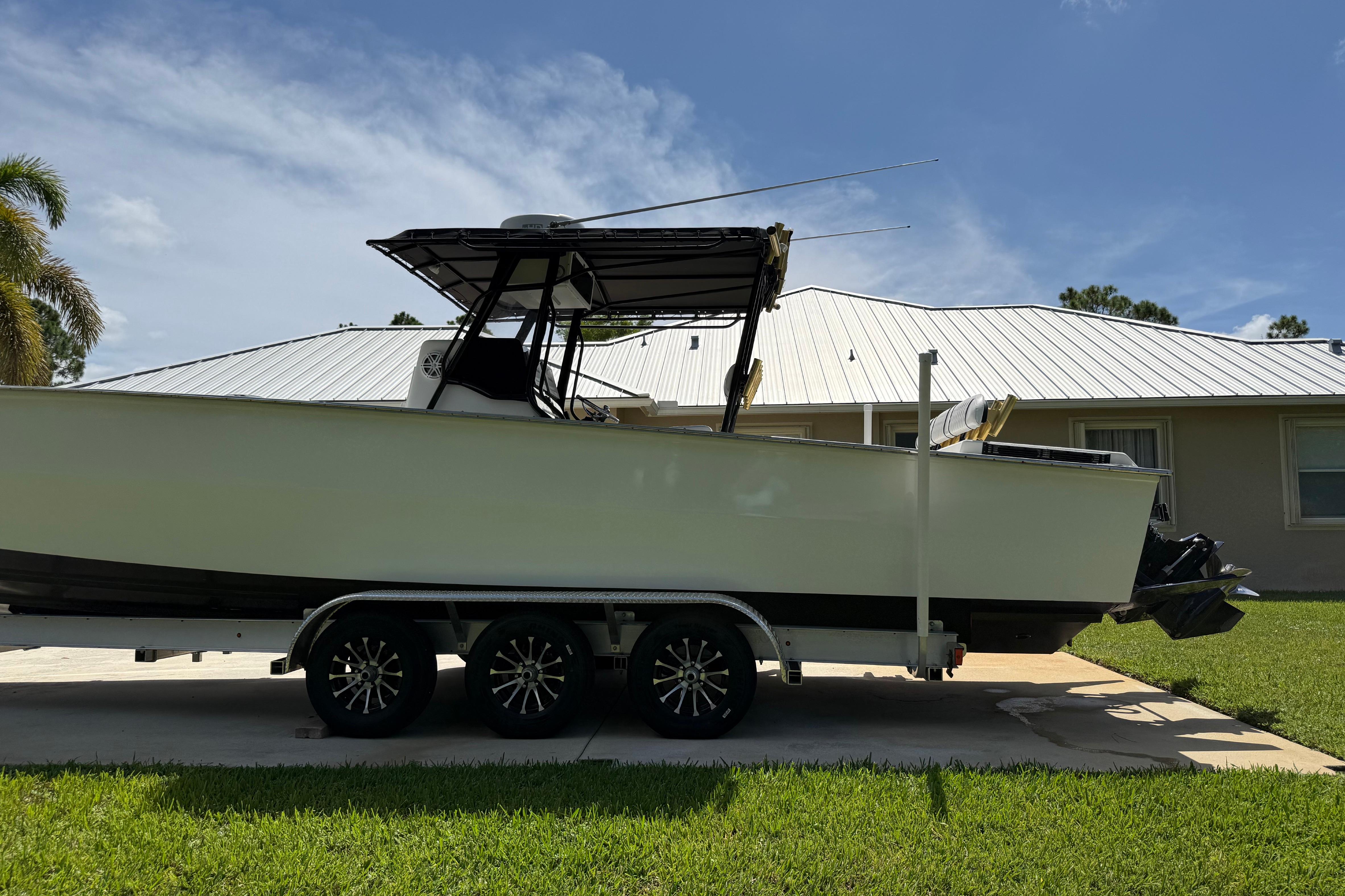 2005 Apache 36CC boat on trailer, parked in front of a house with a metal roof.