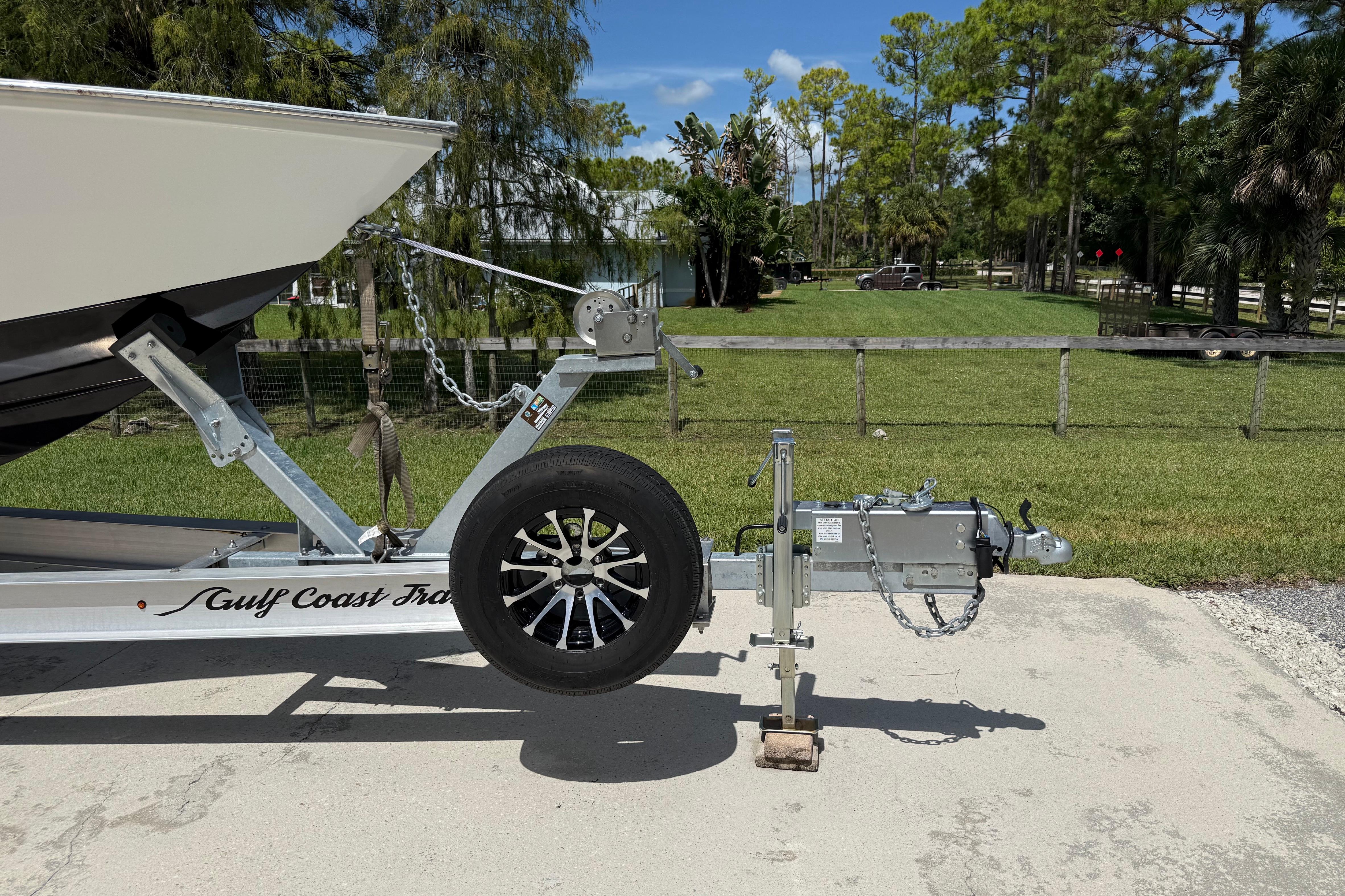 Boat trailer with Apache 36CC, 2005 model, parked on concrete near grassy area.
