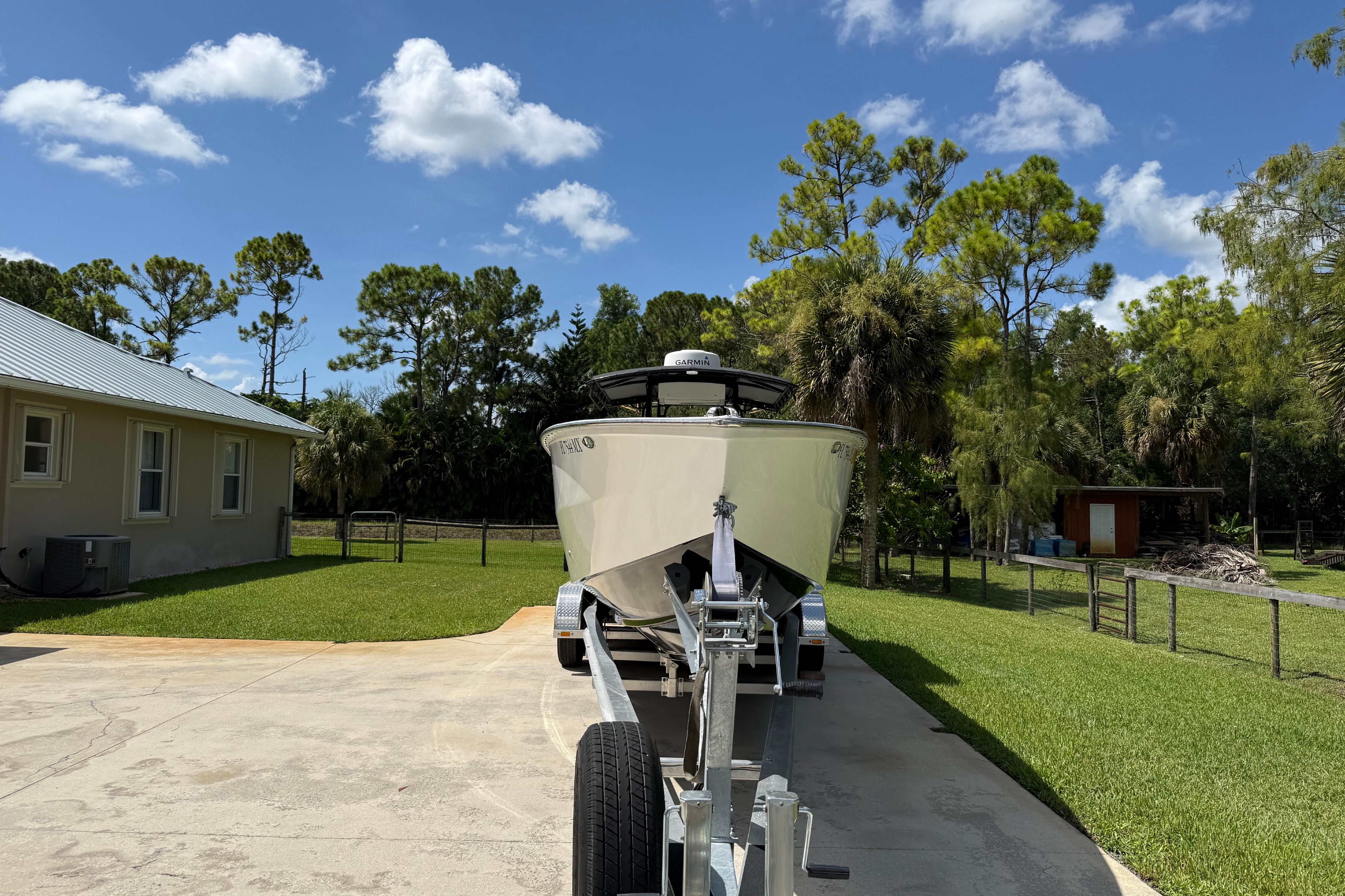 2005 Apache 36CC boat on trailer in sunny driveway, surrounded by trees and house.