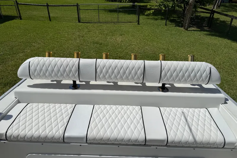  Yacht Photos Pics White quilted seating on 2005 Apache 36CC boat, with rod holders, in a grassy area.