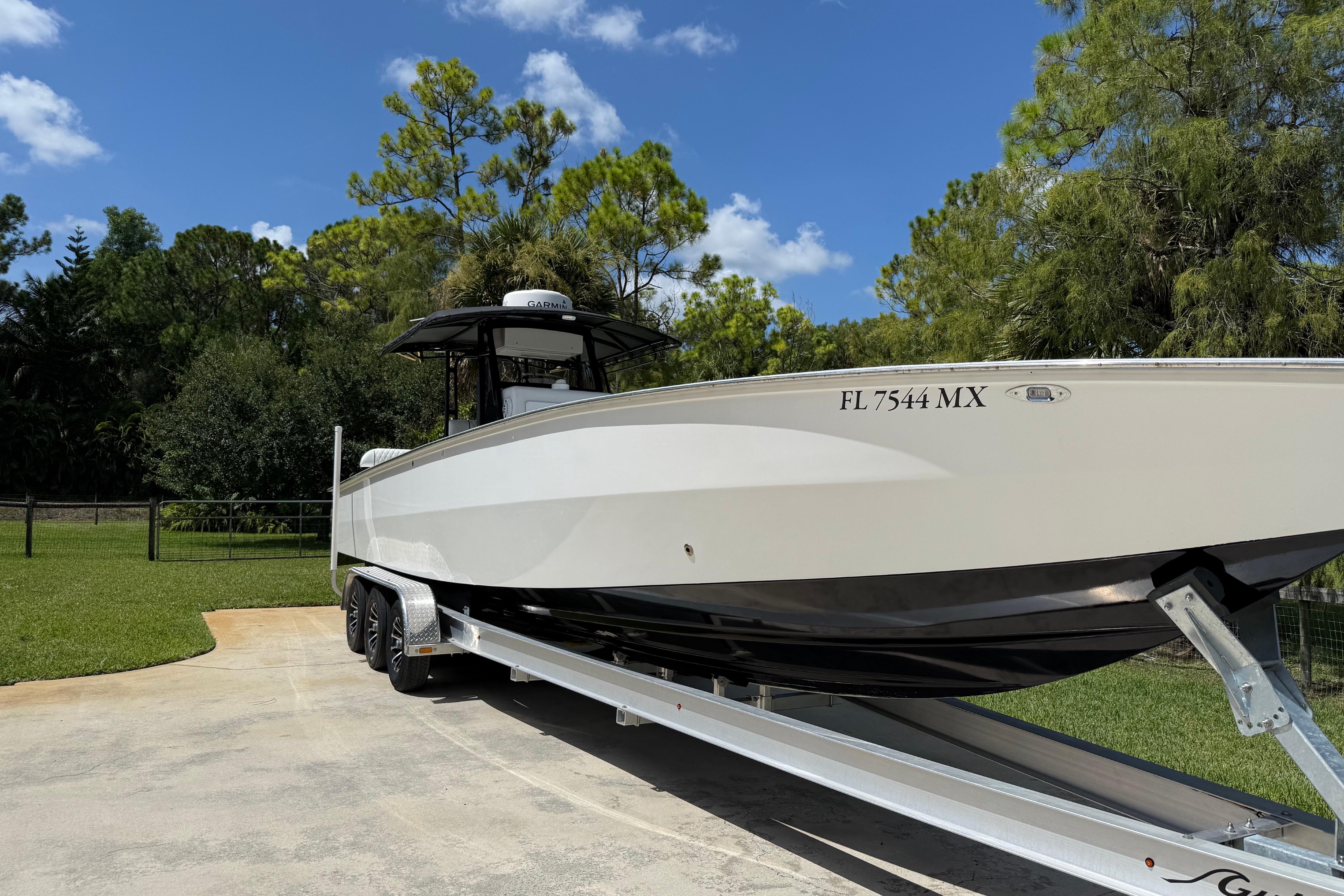 2005 Apache 36CC boat on trailer, parked outdoors under a clear blue sky.