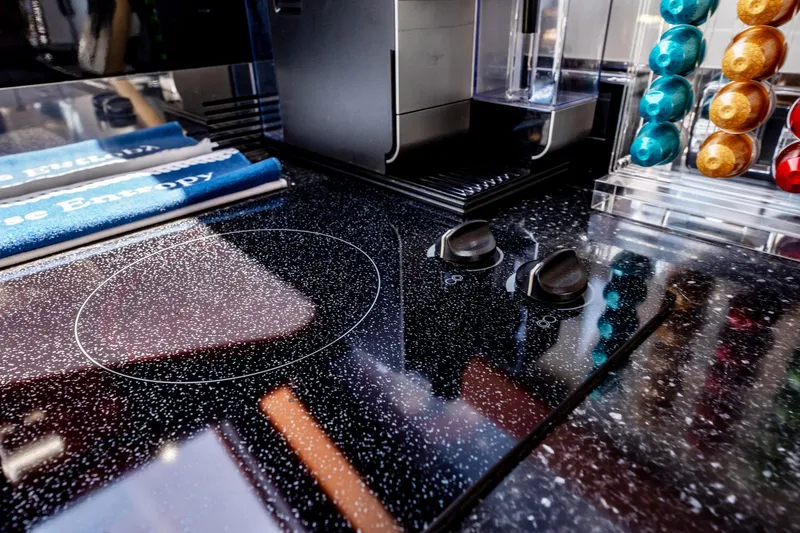 Inverse Entropy Yacht Photos Pics Modern kitchen countertop with electric stove, coffee machine, and colorful coffee pods.