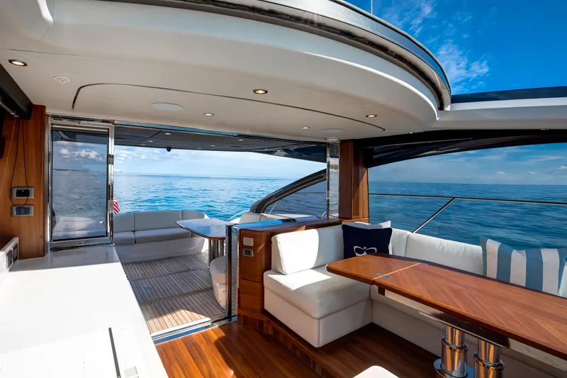 Mermoo Too Yacht Photos Pics Luxurious 2024 Princess V55 yacht interior with ocean view, featuring elegant seating and wooden accents.