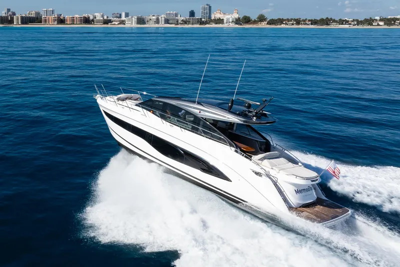 Mermoo Too Yacht Photos Pics 2024 Princess V55 yacht cruising on open water near a city skyline.