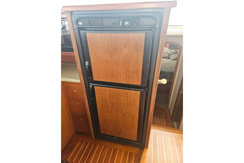 Long Time Comin' Yacht Photos Pics Wood-paneled refrigerator in 2000 Cruisers Yachts 4450 Express Motoryacht interior.