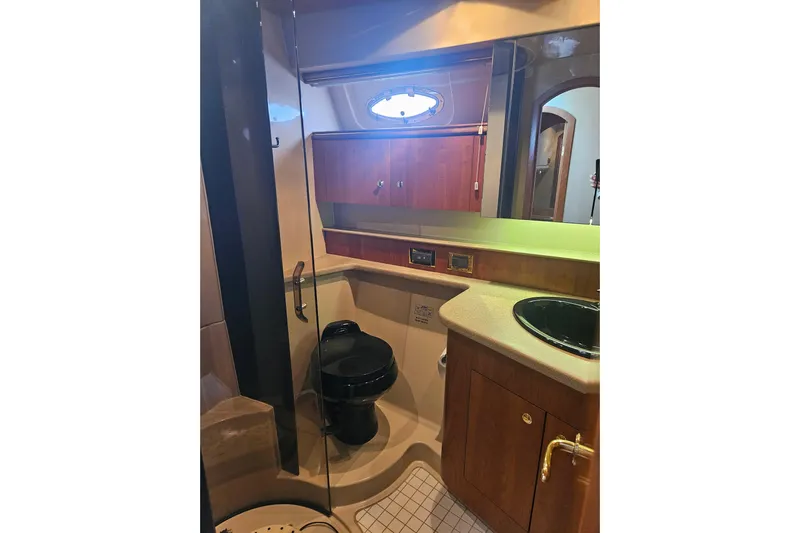 Long Time Comin' Yacht Photos Pics Bathroom interior of 2000 Cruisers Yachts 4450 Express Motoryacht with wooden cabinetry and black fixtures.