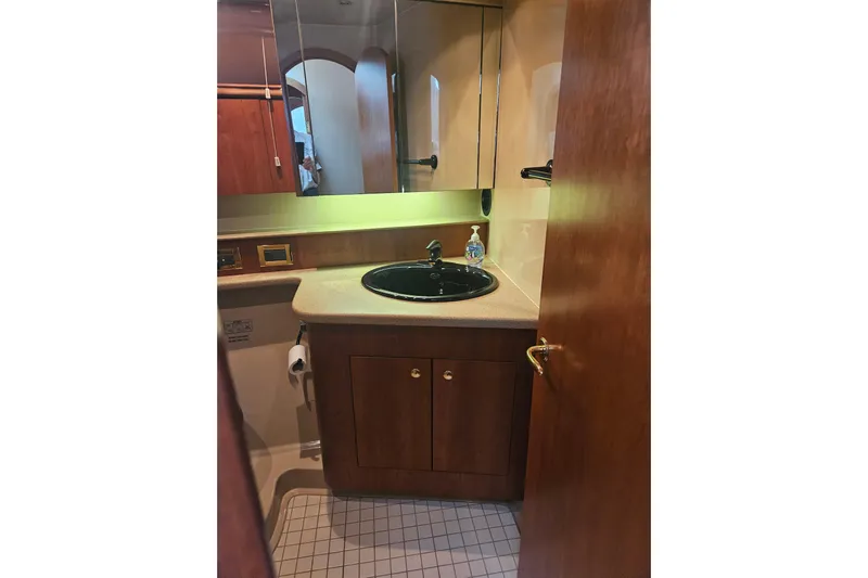 Long Time Comin' Yacht Photos Pics Bathroom interior of 2000 Cruisers Yachts 4450 Express Motoryacht, featuring wood cabinetry and black sink.