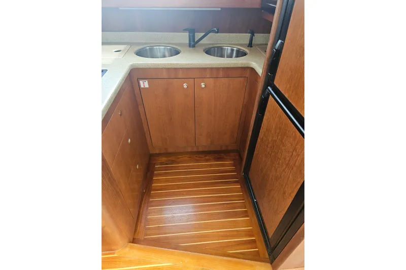 Long Time Comin' Yacht Photos Pics 2000 Cruisers Yachts 4450 Express Motoryacht kitchen with wooden cabinets and dual sinks.