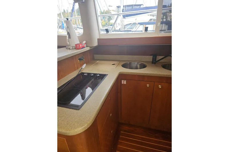 Long Time Comin' Yacht Photos Pics 2000 Cruisers Yachts 4450 Express Motoryacht kitchen with stove, sink, and wooden cabinetry.