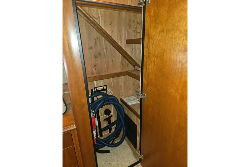 Long Time Comin' Yacht Photos Pics Storage closet inside 2000 Cruisers Yachts 4450 Express Motoryacht, featuring wooden shelves and equipment.