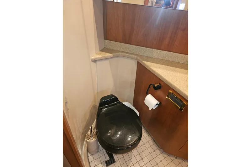 Long Time Comin' Yacht Photos Pics Luxury yacht bathroom with black toilet, wood cabinetry, and tiled floor, 2000 Cruisers Yachts 4450.