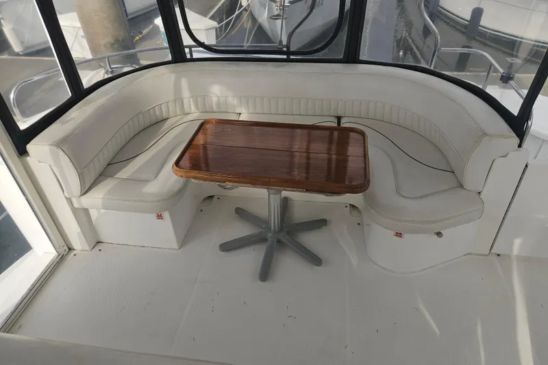 Long Time Comin' Yacht Photos Pics 2000 Cruisers Yachts 4450 Express Motoryacht interior with curved seating and wooden table.