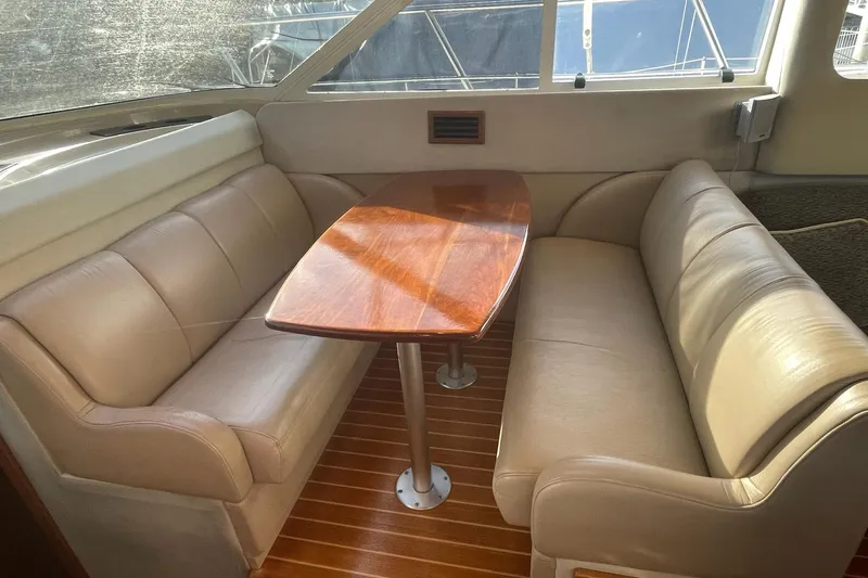 Long Time Comin' Yacht Photos Pics 2000 Cruisers Yachts 4450 Express Motoryacht interior with leather seating and wooden table.