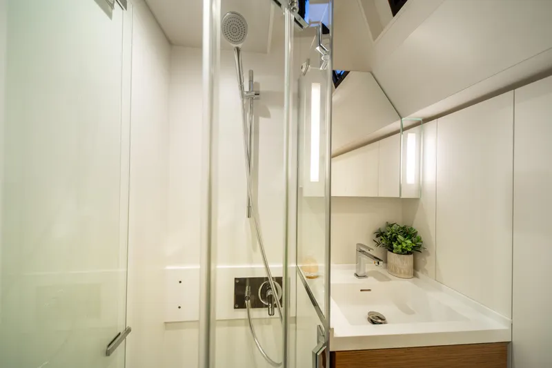 Fortitude Yacht Photos Pics Modern bathroom with glass shower, sleek sink, and plant decor in a 2021 CNB 66 yacht.