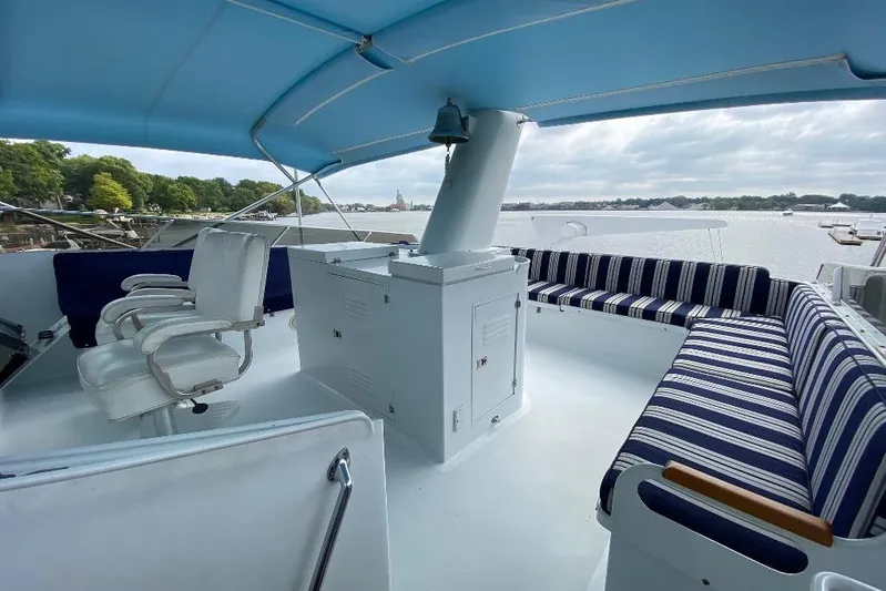  Yacht Photos Pics 1988 Burger 80 Motor Yacht deck with striped seating and helm chairs under blue canopy.