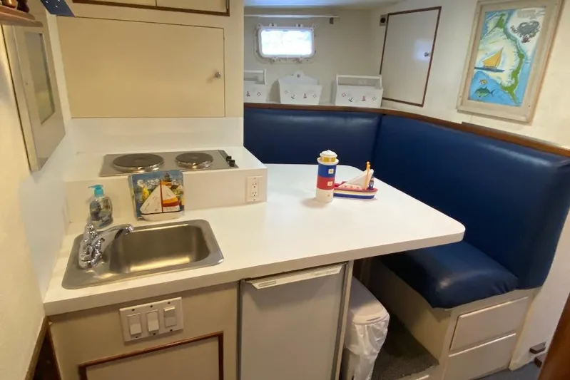  Yacht Photos Pics Compact kitchen and dining area on 1988 Burger 80 Motor Yacht with blue seating and nautical decor.