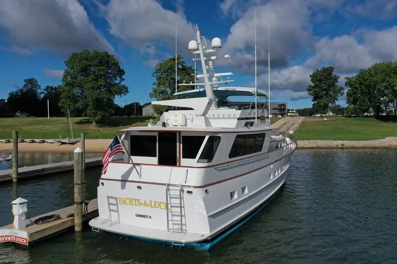  Yacht Photos Pics 1988 Burger 80 Motor Yacht docked, featuring sleek design and American flag, under blue sky.