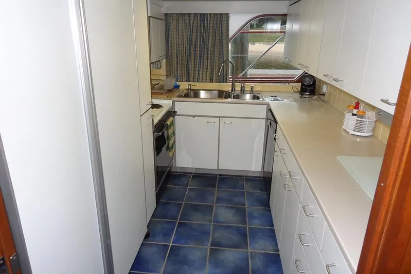  Yacht Photos Pics Galley kitchen in 1988 Burger 80 Motor Yacht with blue tile floor and white cabinets.