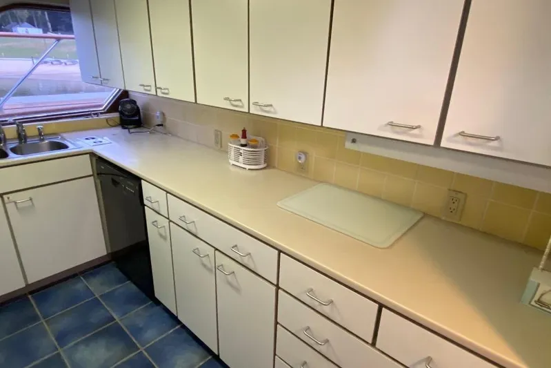  Yacht Photos Pics Kitchen interior of 1988 Burger 80 Motor Yacht with white cabinets and blue tile floor.