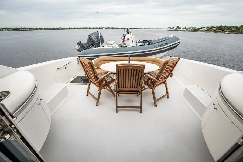 Water Ranch Yacht Photos Pics Luxury yacht deck with wooden chairs and table, featuring a small boat, Lazzara 80 EB, 2003 model.